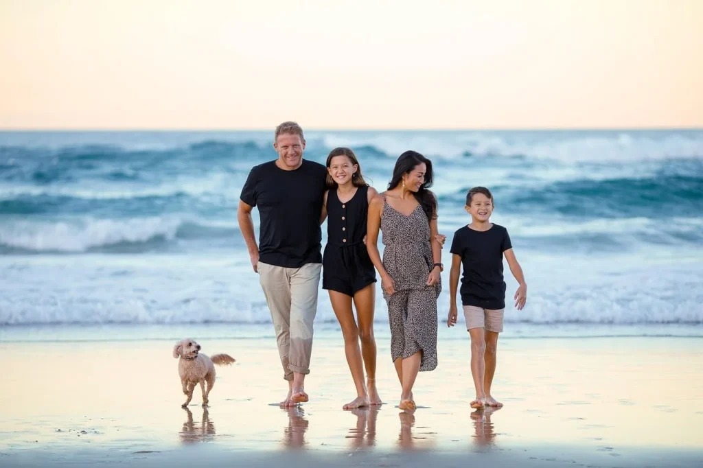 Familia feliz caminando por la playa al atardecer, reflejo de salud y bienestar gracias a los beneficios naturales de la ashwagandha